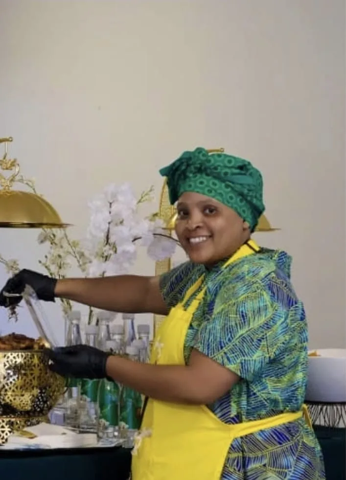 The founder of Luncumo Foods serving from a gold chafing dish at a catered event