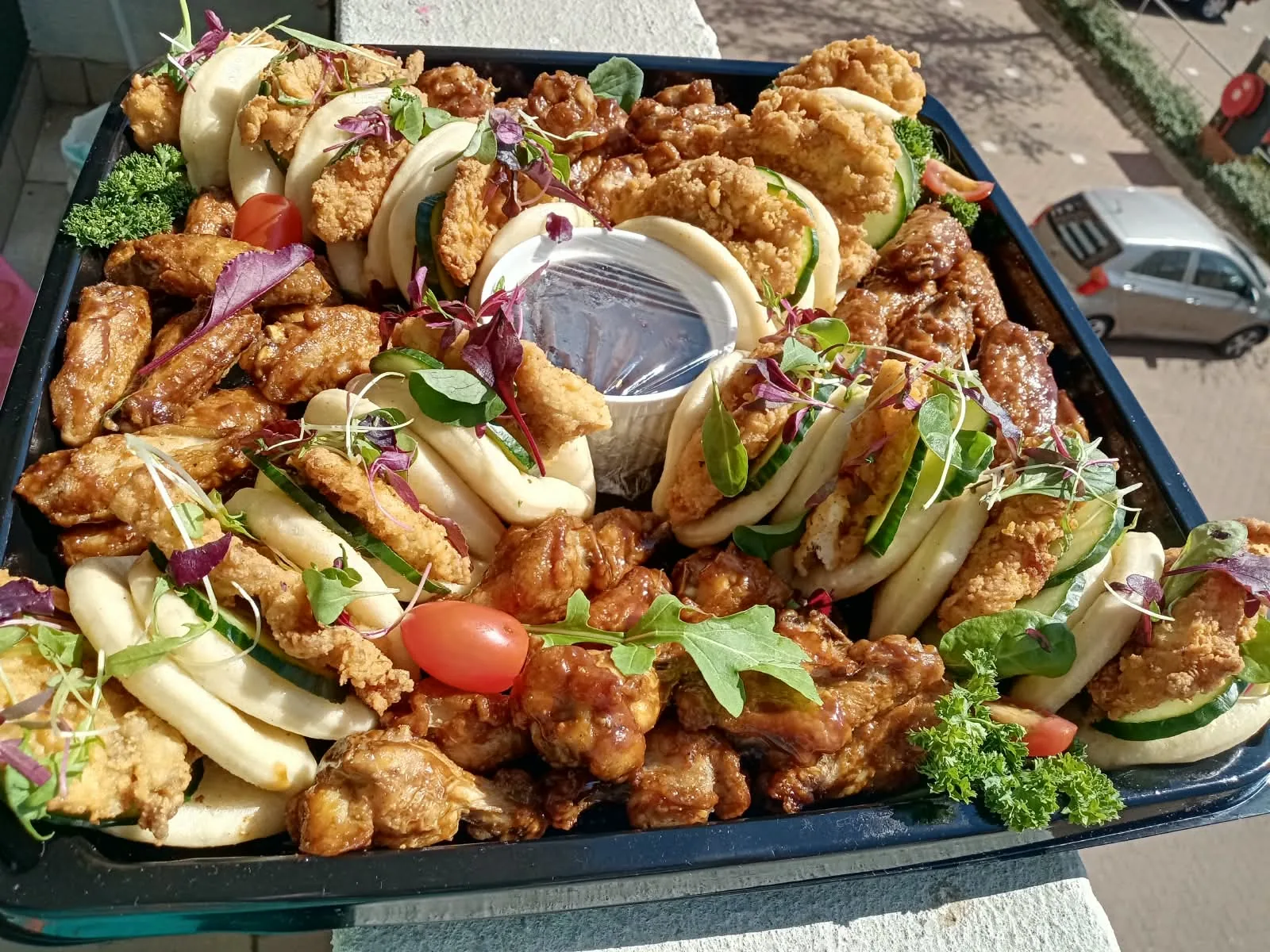 A signature Luncumo savoury platter of bao buns, sticky wings and fresh garnish