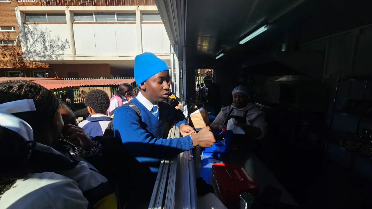 A learner being served at the Luncumo tuckshop window